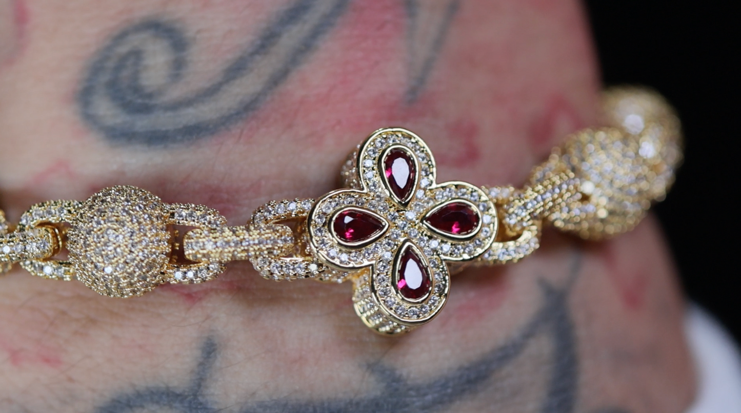 Gold bracelet with red gemstones on a tattooed arm